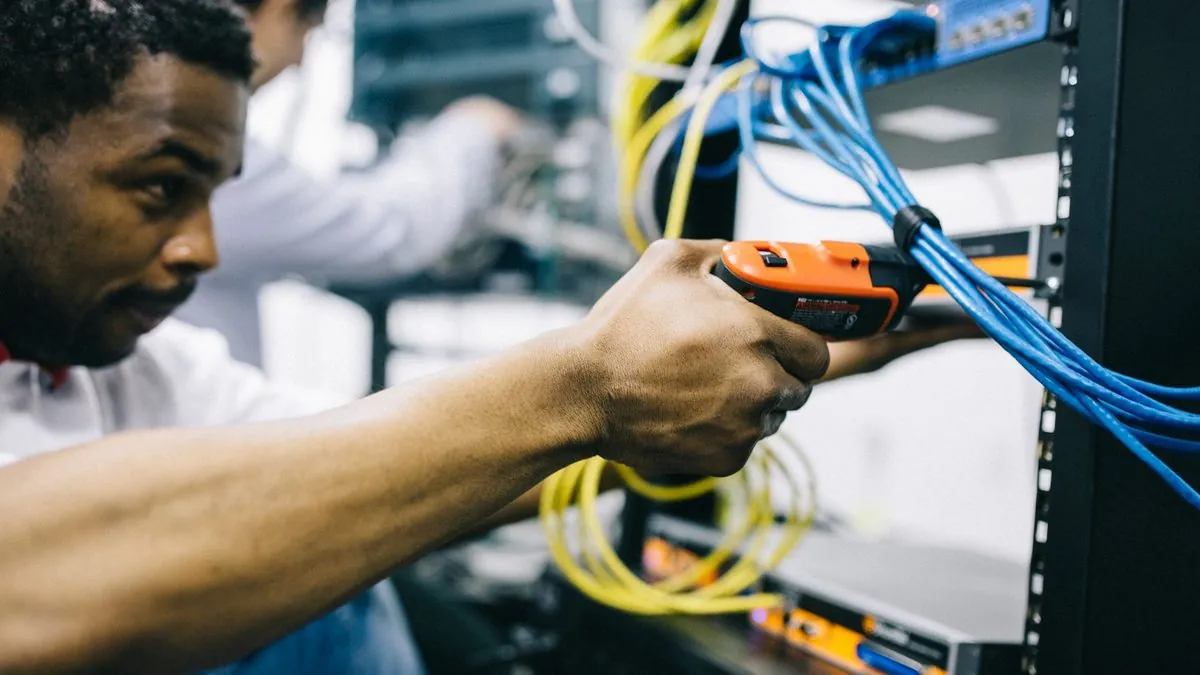 A technician terminating network cables at a server rack while a colleague assists